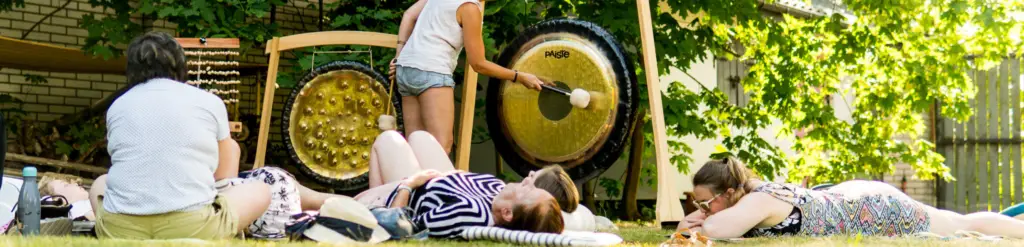 Kobiety leżące na trawie podczas koncertu mis i gongów