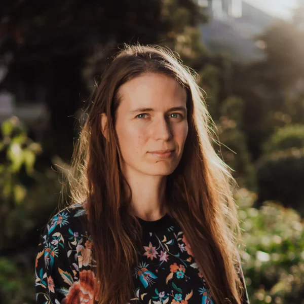 Kobieta w długich, brązowych włosach, ubrana we wzorzystą bluzkę.