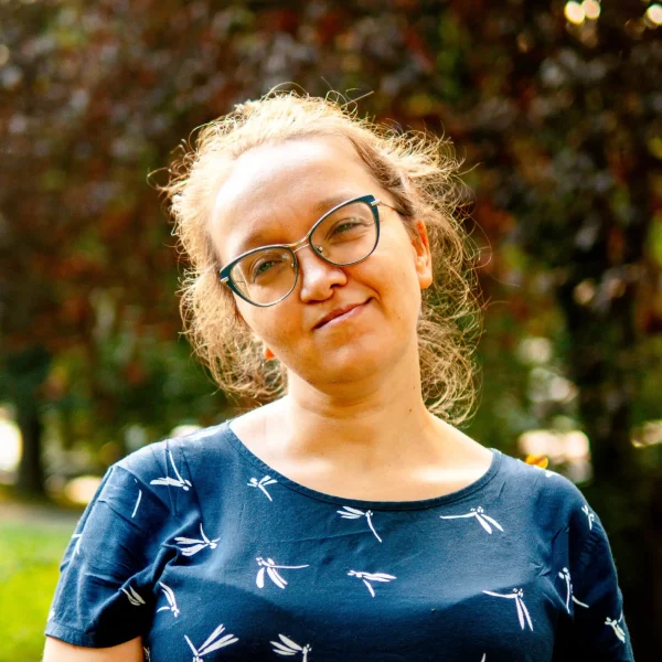 Kobieta w okularach i upiętych włosach, ubrana w niebieską koszulkę.